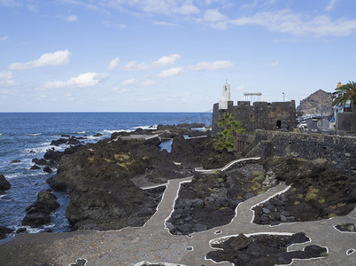 从蓝天白云背景的西班牙特内里费加那利岛看加拉奇科村，那里有海池、熔岩、主干道和防御工事