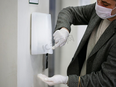 消毒设施摄影照片_戴手套的人用自动酒精分配器清洁细菌和电晕病毒
