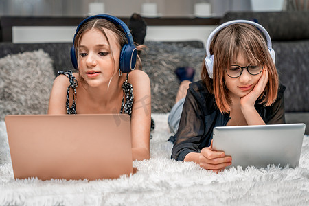 Z世代青春期儿童在家中使用现代科技，使用耳机、笔记本电脑和平板电脑进行娱乐和教育