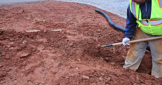 720暴雨摄影照片_工人在暴雨期间挖沟铺设雨水排水管