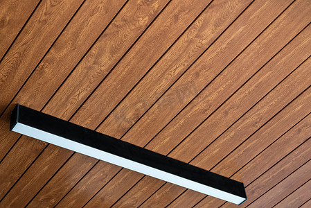 成品仿木凳子摄影照片_PVC 天花板面板覆盖着仿木乙烯基，上面安装了现代照明