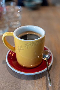 红色碟子摄影照片_桌上的红色碟子上放着黄色杯子的早晨咖啡