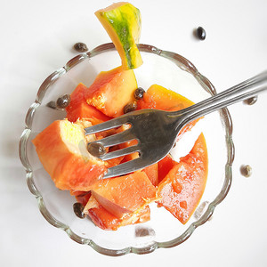 橙色鲜木瓜保存在白色背景中，切块放在带勺子的碗里，富含纤维 维生素 C 和抗氧化剂 增强免疫力 对糖尿病患者和眼睛有益