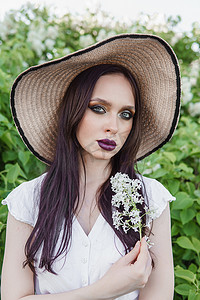 时尚绿色植物摄影照片_一个黑头发的时尚女孩，夏天淡紫色色调的春天肖像。