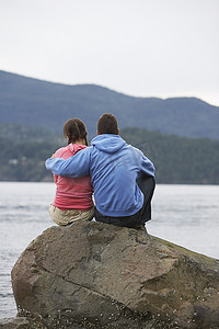 坐在海边岩石上的情侣