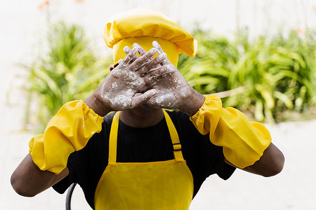 黑人非洲厨师少年双手捧着面粉，闭上脸。