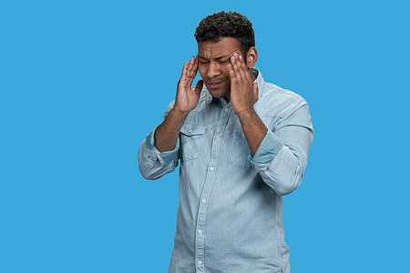 疼痛摄影照片_年轻的印度男子因头痛或偏头痛而摸头。