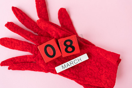 国际黑丝带日摄影照片_漂亮的红色蕾丝手套，上面是木制的立方体，上面刻着 3 月 8 日的字样。假期的准备卡，妇女节。