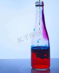 蓝色墨水滴在装有红色液体的玻璃瓶内。