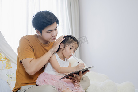小女孩和年轻的父亲正在享受一起使用平板电脑。
