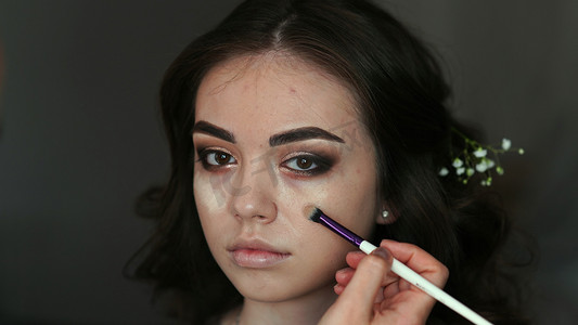 化妆师在模特的脸上涂抹粉底。
