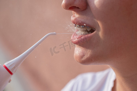 一位戴牙套的女士使用冲洗器。