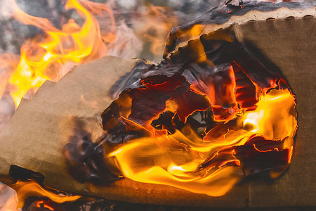 红色火焰燃烧摄影照片_燃烧的纸板箱红橙色火焰，废纸，回收特写