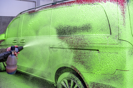 洗车喷头摄影照片_在车库里用绿色活性泡沫洗车