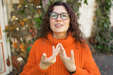 女博主摄影照片_快乐的卷发女博主笑着面对网络摄像头录制视频博客。