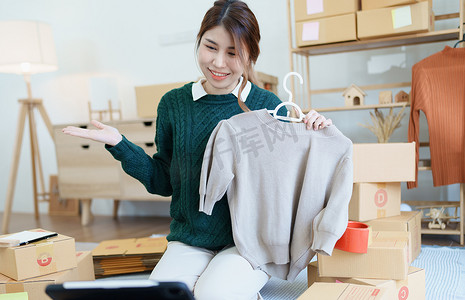 在做出购买决定之前，使用平板电脑向客户展示产品的独立年轻亚洲女性在线卖家的小型企业创业者。