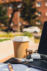 用带无线耳机的纸质笔记本电脑带走工艺回收纸杯中的咖啡。
