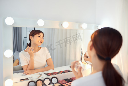 皮肤喷雾摄影照片_快乐的亚洲女人在镜子前喷香水