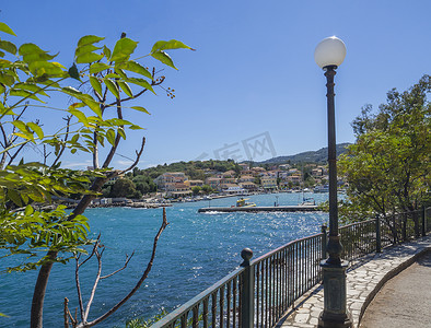Kassiopi 村的码头有灯和树木，享有海港和色彩缤纷的房屋的景色，Kassiopi 是希腊科孚岛北部的旅游村。