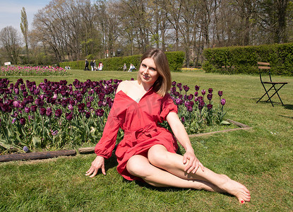 春天公园里一个穿红裙子的年轻美女玩弄头发，调情
