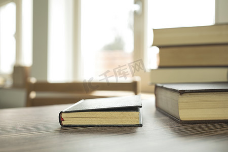 阅读桌摄影照片_教育学习理念，在办公室的家里打开书籍或教科书，在学校书房背景室内的阅读桌和书架过道上堆放成堆的文学文本学术档案