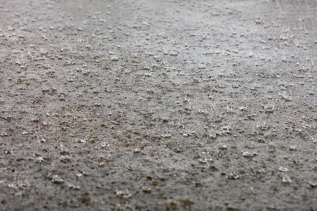 城市大雨摄影照片_大雨点覆盖了城市街道的人行道。