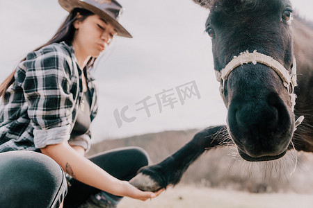 年轻快乐的女人和她的小马在傍晚的夕阳光下。