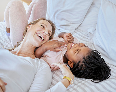 快乐、收养和母亲在床上放松地与孩子交谈、大笑和亲近。