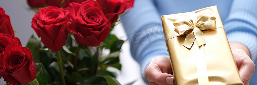 快递员手中的红玫瑰花束和金色礼盒