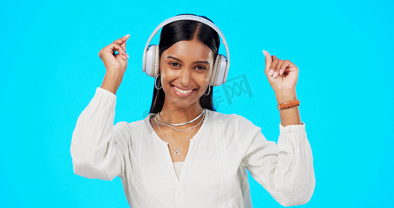 在蓝色工作室背景下，面孔、音乐和戴着耳机、流媒体和幸福的印度女人。