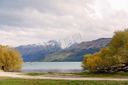 黄色小船摄影照片_有小船和白雪皑皑的阿尔卑斯山的宁静湖