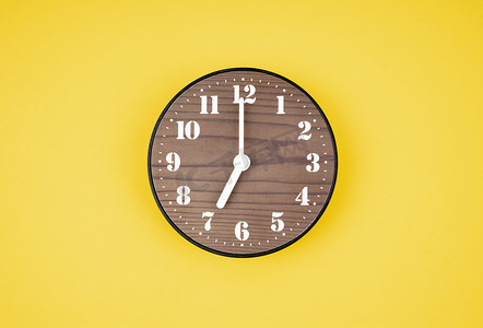 点摄影照片_黄色背景上 7 点钟的复古木钟。