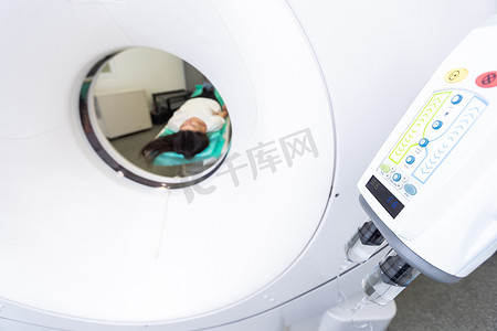 断层扫描仪摄影照片_在医院进行断层扫描测试时躺在 ct 扫描仪床上的美女