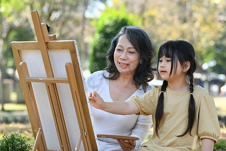 快乐的中年奶奶与可爱的小孙子画画，一起在户外享受休闲周末活动