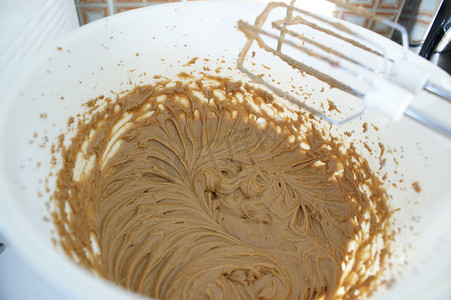 白色碗里的棕色蛋糕面糊，上面有漂亮的图案和厨房搅拌机