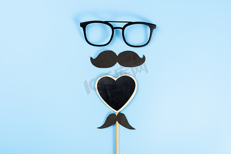 父亲节快乐背景概念，带眼镜、黑色心形和蓝色背景上的黑色胡须，带有文本复制空间。
