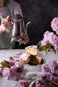 一个女人从银茶壶里倒茶，粉色樱花背景，复活节