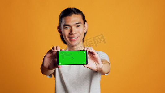 手机横屏背景摄影照片_手持横屏绿屏手机的男模