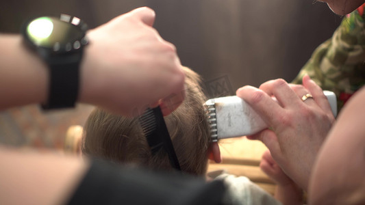 一个小男孩正在用理发机从后脑勺理发。
