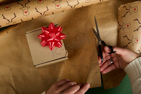 顶视图：用带有鹿图案和红色蝴蝶结的装饰纸包装圣诞礼物。