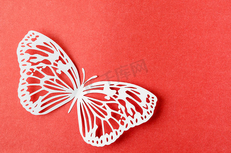 纸蝴蝶雕刻在红色背景上，空间空旷。
