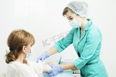 病人验血摄影照片_戴医用口罩的护士包扎病人的手