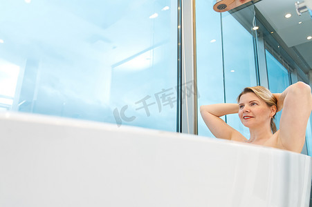 独立浴缸摄影照片_独立的白色浴缸中的女人。