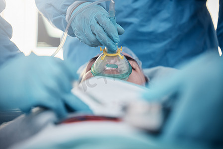 磨砂精华油瓶子摄影照片_医生、外科手术人员和氧气面罩以及穿着磨砂服的医疗队在医院为一名男病人做手术。