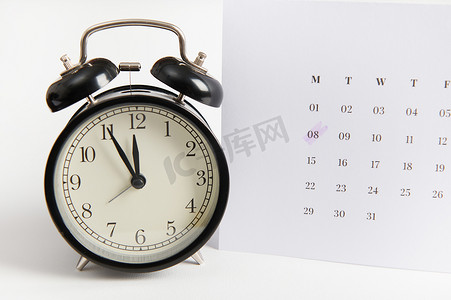 3月倒计时摄影照片_带有标记日期 3 月 8 日的白色日历和白色背景上的黑色闹钟。