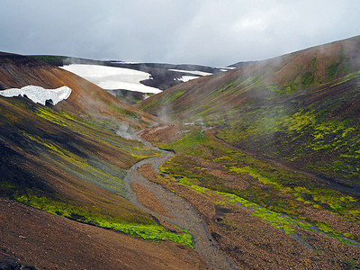冰岛 Landmanalaugar 山冒着热气的地热河流，有绿色的苔藓和雪洞