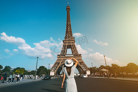 站在巴黎埃菲尔铁塔前戴着太阳帽的女游客的后视图。