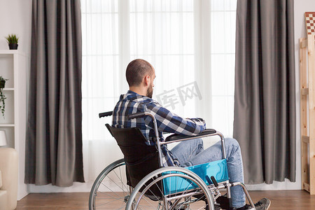 固定不动摄影照片_坐在家里窗户附近的轮椅上