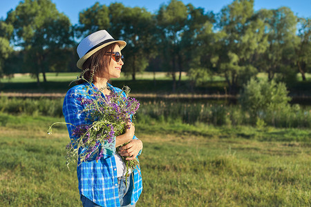 一位戴着帽子、戴着一束野花的成年美女的乡村肖像