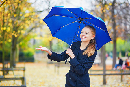 巴黎卢森堡花园秋春雨天带蓝伞的年轻女子